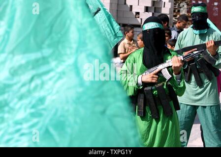 Masked members of Hamas' armed wing, Ezzedine al-Qassam Brigades, hold fake rifles and wear fake explosive belts during a rally in the Jabalya refugee camp in the southern Gaza Strip, on October 24, 2003. Palestinian militant groups Hamas and Islamic Jihad jointly claimed responsibility today for an overnight attack on a Jewish settlement in Gaza that left three Israelis and one of the gunmen dead. (UPI/Ismael Mohammad) Stock Photo