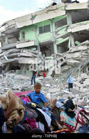 A Palestinian boy sits on the rubble of his home, destroyed by an ...