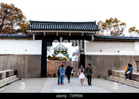Osaka, Japan - April 13, 2019: Castle grounds and gate in evening with people walking by entrance Stock Photo
