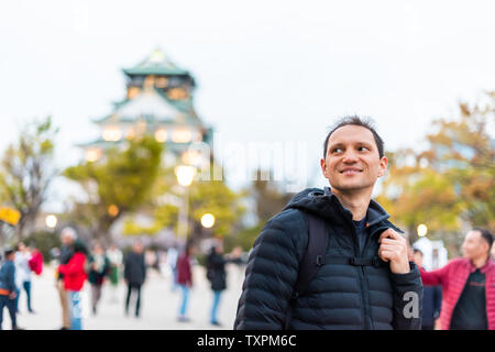 Osaka, Japan castle grounds in evening with happy people man tourist standing by building at night bokeh background Stock Photo