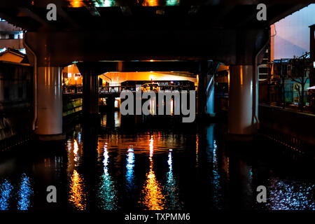 Osaka, Japan downtown with orange and blue lantern lamp illuminated reflection in dark black night river under bridge overpass Stock Photo