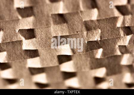 Close-up of a light brown cardboard with cuts that form a pattern of light and shade thanks to direct sunlight Stock Photo