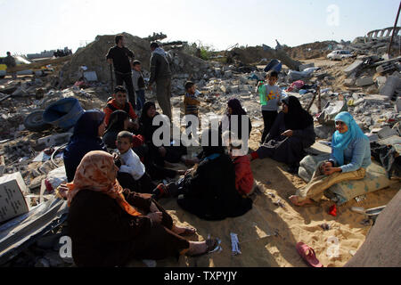A Palestinian family sits on the rubble of their home, destroyed during ...