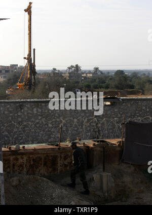 A Member of Hamas's security forces walk by the Palestinian side of the border in the southern Gaza Strip town of Rafah as heavy machinery is seen working on the Egyptian side of the border on December 10, 2009. Israel and Egypt have blockaded Gaza since the militant group Hamas seized power there in 2007. Gaza residents use tunnels to haul in supplies from Egypt. Egyptian engineers are carrying out major excavation work at the Gaza border as an Israeli daily reported that an anti-smuggling barrier was under construction. UPI/Ismael Mohamad Stock Photo