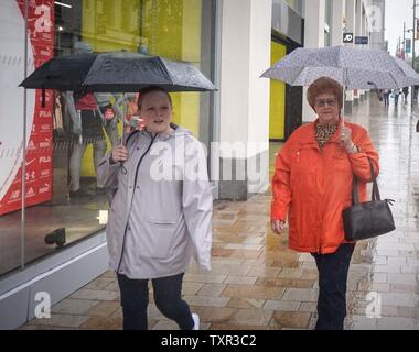 Sheffield, South Yorkshrie, UK. 25th June, 2019. Two women hold an umbrella during a downpour at the Moor Market Credit: Ioannis Alexopoulos/Alamy Live News Stock Photo