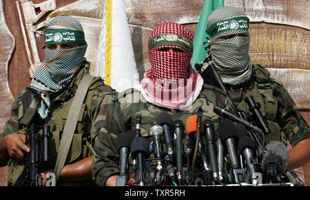 Abu Obaida (C), the spokesman for the Ezzedine Al-Qassam Brigades, the armed wing of Hamas, speaks during a news conference on October 18, 2012 at the Rafah border crossing with Egypt in the southern Gaza Strip to mark the first anniversary of a deal which saw the exchange of 1,027 Palestinian prisoners for captured Israeli soldier Gilad Shalit. The snatching of Israeli soldier Gilad Shalit in June 2006 by a group of Hamas militants and others sparked a more than five-year crisis for Israel, which finally ended on October 18, 2011. UPI/Ismael Mohamad Stock Photo