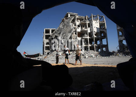 Palestinian men walk past a destroyed apartment building during a cease-fire between Gaza and Israel, in the town of Beit Lahiya, northern Gaza Strip, August 12, 2014. UPI/Ismael Mohamad Stock Photo