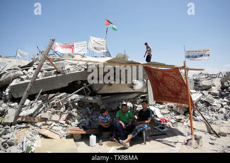 Palestinian youths sit in a makeshift tent amid the rubble of their destroyed house in Al Shejaeiya neighbourhood in the east of Gaza City, August 28, 2014. An indefinite ceasefire to end seven weeks of fighting between Israel and Palestinian militant groups in the Gaza Strip was holding with Hamas declaring 'victory'. UPI/Ismael Mohamad Stock Photo