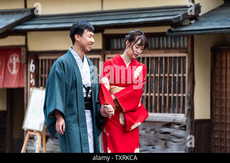 Nara, Japan - April 14, 2019: Young people tourists couple walking on sidewalk street road in downtown city dressed up in kimono costume Stock Photo