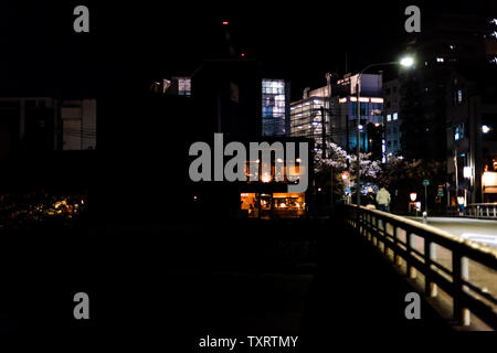 Kyoto, Japan - April 16, 2019: Street bridge near Gion district at night with illuminated buildings restaurant in dark black night Stock Photo