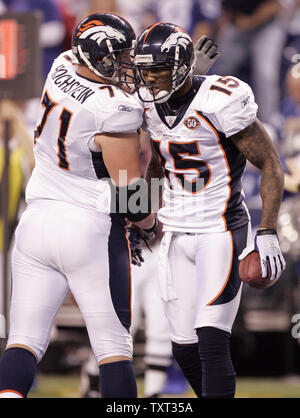 New England Patriots quarterback Tom Brady (R) behind his center Russ  Hochstein (C) faces off against Denver Broncos tackle Gerard Warren (L)  during the AFC divisional playoff game at Invesco Field in