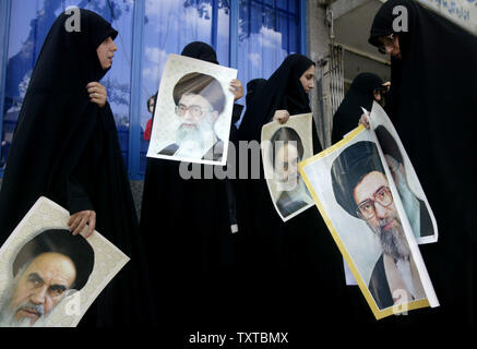 Iranian women hold pictures of Iran's late supreme leader Ayatollah Rohollah Khomeini (L) and Iran's supreme leader Ayatollah Ali Khamenei as they demonstrate in front of the office of Iran's nuclear negotiator to protest Iran's planned talks with the United Nations regarding its nuclear progra, in Tehran on April 8,2006.   (UPI Photo/Mohammad Kheirkhah) Stock Photo