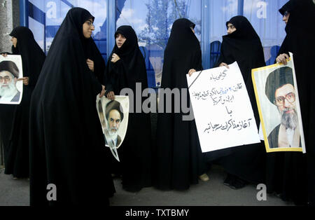 Iranian women hold pictures of Iran's late supreme leader Ayatollah Rohollah Khomeini (L) and Iran's supreme leader Ayatollah Ali Khamenei as they demonstrate in front of the office of Iran's nuclear negotiator to protest Iran's planned talks with the United Nations regarding its nuclear progra, in Tehran on April 8,2006.   (UPI Photo/Mohammad Kheirkhah) Stock Photo