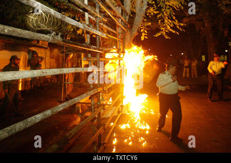 An Iran police officer avoids a molotov cocktail thrown at the front of the Danish Embassy by members of Iran's hardline Islamist Basij militia in Tehran on October 10, 2006.  Danish television broadcast video footage of  a Danish political youth group that was deemed insulting to the Muslim Prophet Mohammad.  Protesters hurled stones and petrol bombs into the embassy compound.  (UPI Photo/Mohammad Kheirkhah) Stock Photo