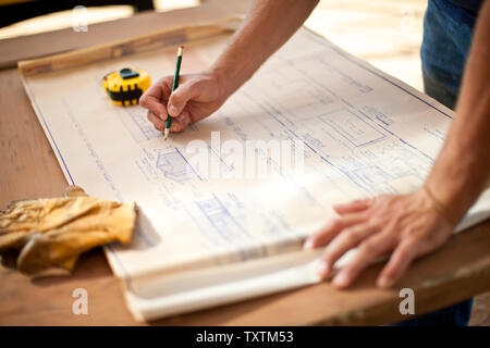 Hands of a builder making notes on a building blueprint. Stock Photo