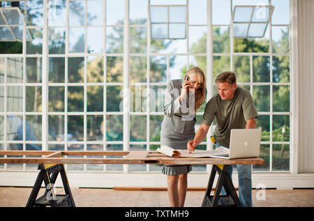Mid adult builder making notes on a  blue print. Stock Photo