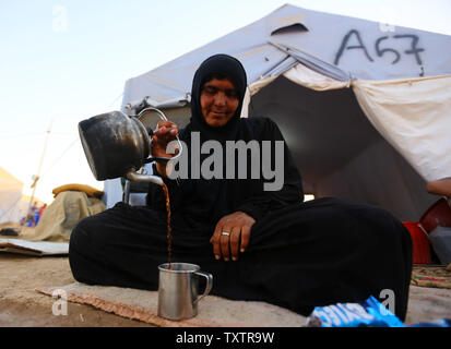 Iraqi refugee woman drink tea inside the Khazer refugee camp on the outskirts of Arbil, in Iraq's Kurdistan region, June 20, 2014.Tens of thousands of people have fled Iraq's second largest city of Mosul after it was overrun by ISIS (Islamic State of Iraq and Syria) militants. Many have been temporarily housed at various IDP camps around the region including the area close to Erbil, as they hope to enter the safety of the nearby Kurdish region. UPI/Ceerwan Aziz Stock Photo