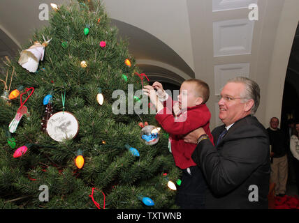 Missouri Governor Jay Nixon lifts Bishop Benson (5) up to place a ornament on the offical Christmas tree during a decorating ceremony in the State Capitol Building in Jefferson City, Missouri on December 3, 2010. Kindergartner's from the nearby Ceder Hill Elementary School helped the Governor decorate the eight-foot, scotch pine tree. UPI/Bill Greenblatt Stock Photo