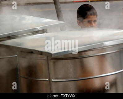 An Ultra-Orthodox Israeli boy walks by barrels of boiling water used   to kosher cooking utensils for the upcoming Passover holiday, in the religious neighborhood, Mea Shearim, in Jerusalem, April 20, 2005. Jews will observe the Passover seder on the evening of April 23 when they will remember the liberation  and exodus of the Hebrew slaves from Egypt. (UPI Photo/Debbie Hill) Stock Photo