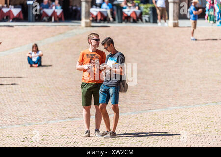Siena, Italy - August 27, 2018: Piazza in old town village in Tuscany with two people young tourists walking on square Stock Photo