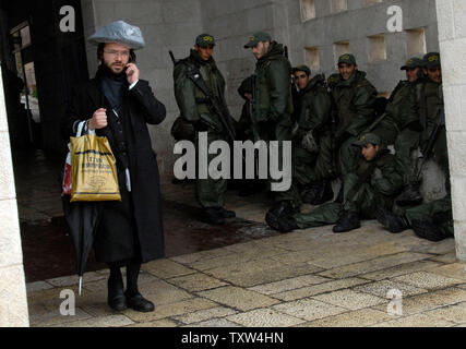 An Ultra-Orthodox Jew walks by Israeli border police in Jerusalem, January 8, 2008, one day before the arrival of US President George W. Bush to the region.  (UPI Photo/Debbie Hill) Stock Photo