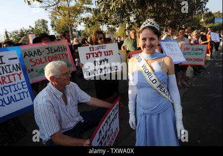 Australian actress Jane Corman wears an evening gown as 'Miss World Peace' near Palestinian, Israeli and international activists during a protest against a Jewish settlement  in the east Jerusalem neighborhood of Sheikh Jarrah, November 12, 2010. Activists marked the one year anniversary of weekly demonstrations in support of Palestinians evicted from their homes in Sheikh Jarrah by Israel.   - UPI/Debbie Hill Stock Photo