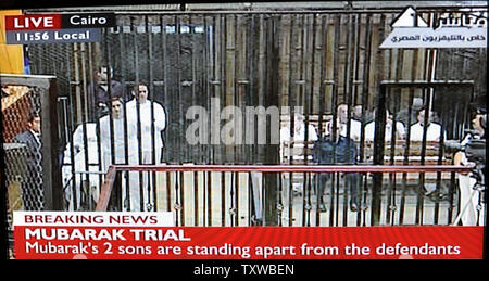 Video image taken from Egyptian State Television shows former Egyptian President Hosni Mubarak, 83, wearing white prison clothes,in a hospital bed  with his two son, Alaa and Gamal inside a cage in a Cairo courtroom, August 3, 2011. Mubarak and his two sons, Alaa and Gamal, are being tried on charges of corruption and ordering the killing of protesters during the revolution that ended his reign after 18 days of popular protest. UPI/Debbie Hill Stock Photo