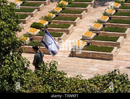 An Israeli carries the national flag during the funeral of American-Israeli soldier Max Steinberg, 24, in the military cemetery on Mt. Herzl in Jerusalem, Israel, July 23, 2014.  Steinberg, a native of Los Angeles, California, immigrated to Israel and enlisted in the Israel Defense Forces in 2012, where he served as a sharpshooter in the elite Golani Brigade. He was among the 13 soldiers killed by Palestinian militants in the Gaza Strip on Sunday. Twenty-nine Israeli troops have been killed since the army launched a ground incursion into Gaza last week. More than 30,000 people attended the fun Stock Photo