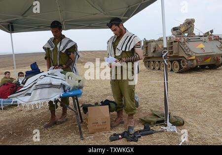 Israeli soldiers wear the traditional Jewish prayer shawl while praying in the morning beside an armored personnel carrier at a staging area at an unspecified  location near the Israeli border with the Gaza Strip in southern Israel,  July 28, 2014.  Fighting between Israel and Hamas was quieter on the first day of the Muslim holiday of Eid Al Fitr, after pressure from the UN Security Council and US President Barak Obama for an immediate ceasefire.  UPI/Debbie Hill Stock Photo