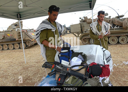 Israeli soldiers wear the traditional Jewish prayer shawl while praying in the morning beside an armored personnel carrier at a staging area at an unspecified  location near the Israeli border with the Gaza Strip in southern Israel,  July 28, 2014.  Fighting between Israel and Hamas was quieter on the first day of the Muslim holiday of Eid Al Fitr, after pressure from the UN Security Council and US President Barak Obama for an immediate ceasefire.  UPI/Debbie Hill Stock Photo