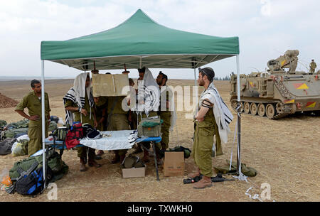 Israeli soldiers wear the traditional Jewish prayer shawl while praying in the morning beside an armored personnel carrier at a staging area at an unspecified  location near the Israeli border with the Gaza Strip in southern Israel,  July 28, 2014.  Fighting between Israel and Hamas was quieter on the first day of the Muslim holiday of Eid Al Fitr, after pressure from the UN Security Council and US President Barak Obama for an immediate ceasefire.  UPI/Debbie Hill Stock Photo