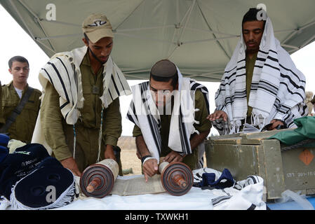 Israeli soldiers wear the traditional Jewish prayer shawl while praying with the torah scroll at a staging area at an unspecified  location near the Israeli border with the Gaza Strip in southern Israel,  July 28, 2014.  Fighting between Israel and Hamas was quieter on the first day of the Muslim holiday of Eid Al Fitr, after pressure from the UN Security Council and US President Barak Obama for an immediate ceasefire.  UPI/Debbie Hill Stock Photo