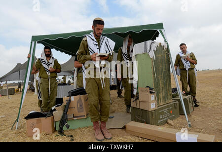 Israeli soldiers wear the traditional Jewish prayer shawl during morning prayers at an army staging area at an unspecified  location near the Israeli border with the Gaza Strip in southern Israel,  July 28, 2014.  Fighting between Israel and Hamas was quieter on the first day of the Muslim holiday of Eid Al Fitr, after pressure from the UN Security Council and US President Barak Obama for an immediate ceasefire.  UPI/Debbie Hill Stock Photo