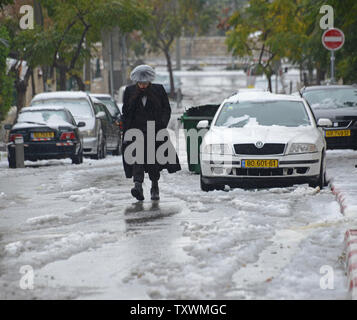 An Ultra-Orthodox Jew walks in the snow and rain during a winter storm in Jerusalem, Israel, January 8, 2015.  A heavy winter storm is hitting the Middle East, while only 5 cm. or 1 inch of snow fell in Jerusalem. UPI/Debbie Hill Stock Photo