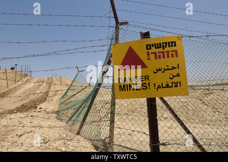 Barbed wire and Danger Mines sign hangs on a fence blocking the entrance to churches near the Jordan River at the Qasr al Yahud baptism site, near Jericho in the West Bank, August 3, 2016. The traditional site of the baptism of Jesus by John the Baptist is surrounded by fields of land mines left after the Six Day War in 1967. Several churches are not accessible to pilgrims because they are located behind barbed wire for five decades. Israelis and Palestinians have made a rare agreement to allow a UK anti-mine group, The HALO Trust, to soon begin to clear some 4,000 land mines. This will eventu Stock Photo