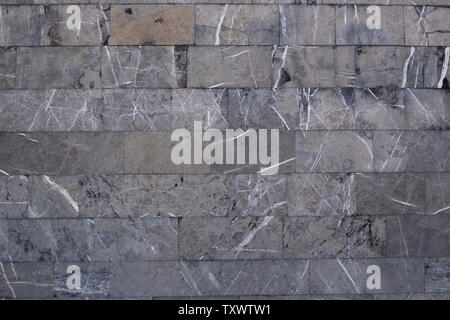 Background from gray marble blocks. A wall of rough stone with black potholes and white lines Stock Photo