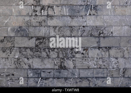 Background from gray marble blocks. A wall of rough stone with black potholes and white lines Stock Photo