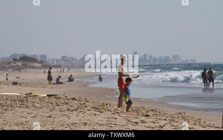 The skyline of Gaza is seen in the distance, as Israelis enjoy the beach on the Mediterranean Sea near Kibbutz Zikim, on the Israeli-Gaza border, June 22, 2017.  This week Israeli's National Electric Company cut it's limited electricity supply to the Gaza Strip after the Palestinian Authority refused to pay Hamas' electricity bills. On Wednesday, Egypt supplied 1.1 million liters of diesel fuel to Gaza, which is expected to last four days, running at 50 percent it's capacity. Photo by Debbie Hill/UPI Stock Photo