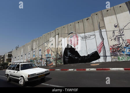 A Palestinian drives past graffiti of U.S. President Donald Trump on Israel's controversial separation wall in the biblical city of Bethlehem, West Bank, August 9, 2017. The graffiti depicts Trump wearing a Jewish skullcap and thinking 'I'm going to build you a brother' in reference to the wall he has promised to build on the Mexican border.   -   Photo by Debbie Hill/UPI Stock Photo