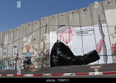 A Palestinian walks past graffiti of U.S. President Donald Trump on Israel's controversial separation wall in the biblical city of Bethlehem, West Bank, August 9, 2017. The graffiti depicts Trump wearing a Jewish skullcap and thinking 'I'm going to build you a brother' in reference to the wall he has promised to build on the Mexican border.   -   Photo by Debbie Hill/UPI Stock Photo