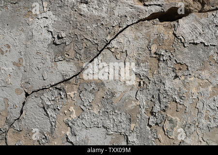 Old textured concrete wall with traces of putty, peeling paint and large cracked Stock Photo