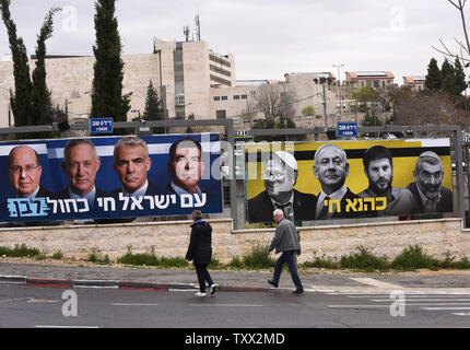 People walk past election billboards, put up by the new Israeli centrist Blue and White party, featuring Israeli Prime Minister Benjamin Netanyahu (second from the left in right billboard) with extreme ultra-nationalist right wing politicians, in Jerusalem, Israel, March 24, 2019. The words in Hebrew read 'Kahana Lives' in reference to the ultra-nationalist party that was banned from the government in 1994. The billboard on the left shows the leaders of the Blue and White party (L-R) Moshe Yaalon, Benny Gantz, Yair Lapid, and Gabi Ashkenazi and in Hebrew reads 'The Nation of Israel Lives.'  Is Stock Photo