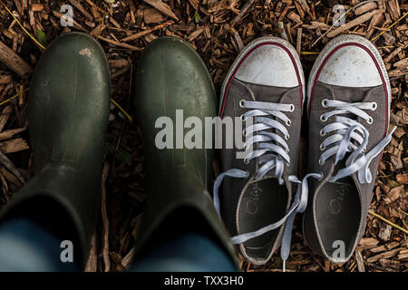 Switching from comfy casual sneakers to garden work boots. Getting ready for gardening. Concept of city to country. Stock Photo