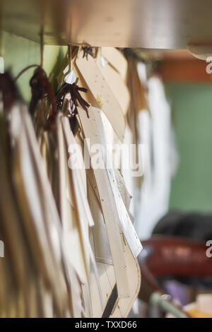 Professional tailor paper template set hanging on the wall in the workshop. Manufacturing leather goods, craft products. Stock Photo