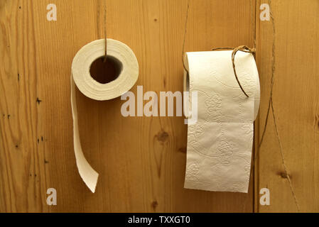 white toilet paper hangs on a wooden wall Stock Photo