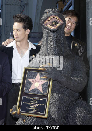 Film character 'Godzilla' holds a replica plaque while posing with Japanese actor Masahiro Matsouka (L) and director Ryuhei Kitamura during an unveiling ceremony to receive the 2,271st star on the Hollywood Walk of Fame in Hollywood, California November 29, 2004. The movie icon celebrates its 50th anniversary with the star as well as the premiere of the film 'Godzilla Final Wars' later in the day.   (UPI Photo/Jim Ruymen) Stock Photo