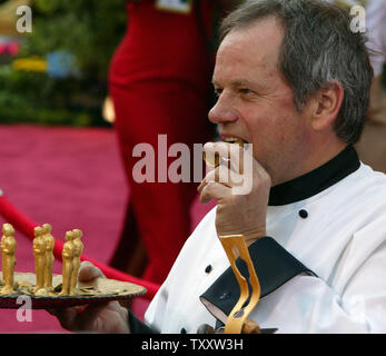 Celebrity chef Wolfgang Puck takes a bite out of a chocolate Oscar award as he arrives for the 77th Annual Academy Awards held at the Kodak Theater, February 29, 2004, in Los Angeles.    (UPI Photo/Terry Schmitt) Stock Photo