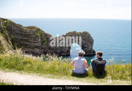 A old lady and young man enjoying the sea view at Durdle Door on a sunny afternoon
