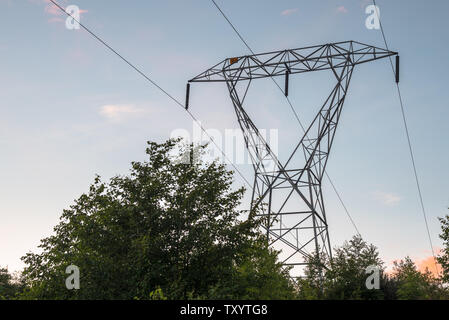 High voltage electricity pylon against clear sky at sunset Stock Photo