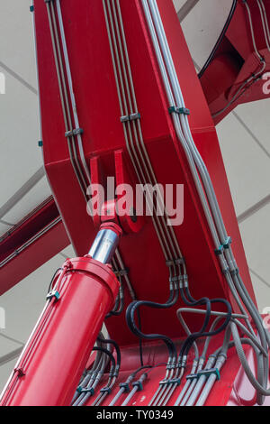 Red hydraulic cylinder with associated piping and hoses at an installation in the Yaletown district of Vancouver British Columbia Stock Photo